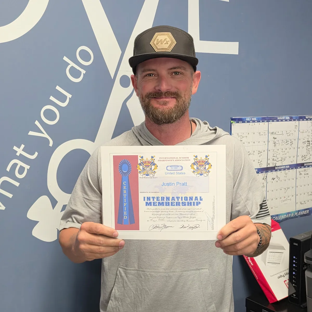 Justin Pratt holding his International Scissor Sharpeners Association membership certificate